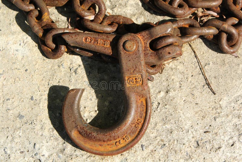 Old Rusty Iron Chain with a Hook Lies on a Rough Surface Stock Photo