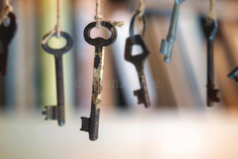 Old rusty keys hanged on the ropes with blurred book shelf background stock images Old rusty keys hanged on the ropes with blurred book shelf background stock images