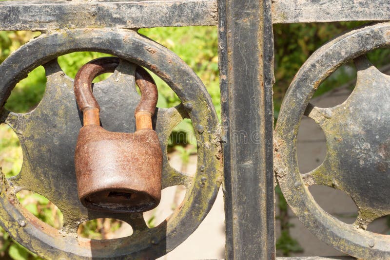 Old rusty lock on a metal gate into the garden. Lock on the iron gate. Symbol imprisonment and slavery. Property security chain
