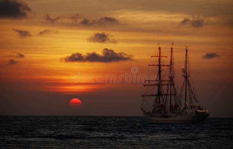 Old sailing ship in the sea at sunset