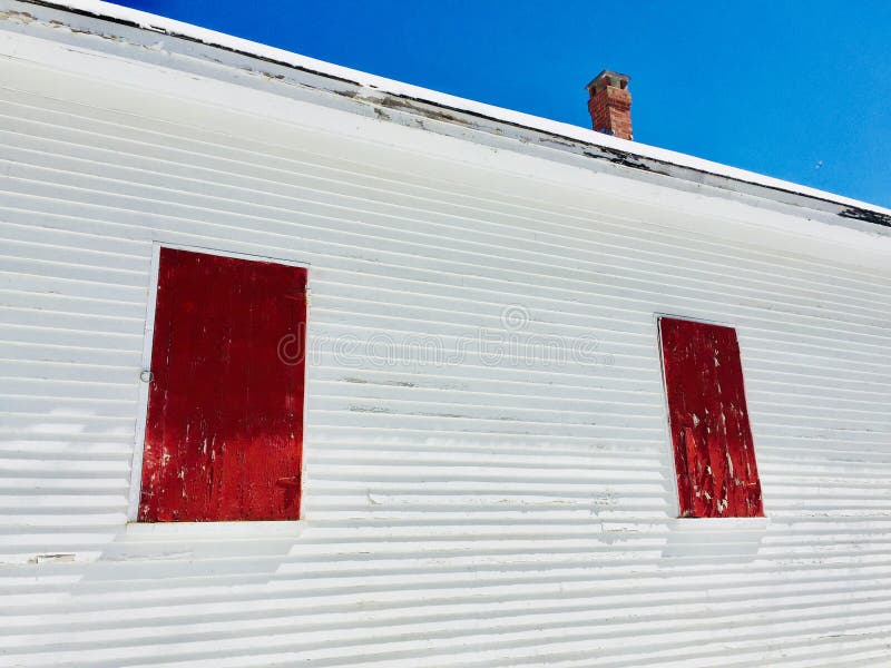 Old schoolhouse with chimney and red window shutters. Old schoolhouse with chimney, blue sky, and bright red window shutters in central maine royalty free stock photos Old schoolhouse with chimney and red window shutters. Old schoolhouse with chimney, blue sky, and bright red window shutters in central maine royalty free stock photos