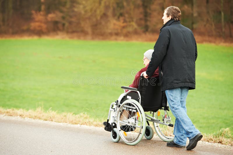 Old senior woman in wheelchair with careful son