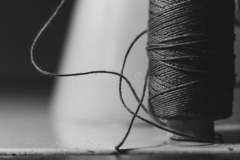 Old sewing machine needle with black thread, on a old grungy work table. Tailor`s work table. textile or fine cloth making. indust