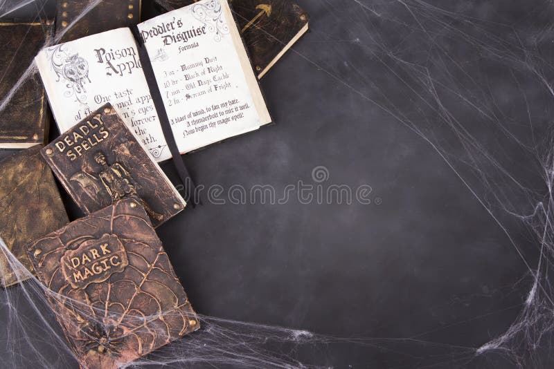 Old spell books with spider webs on a chalkboard background for Halloween.