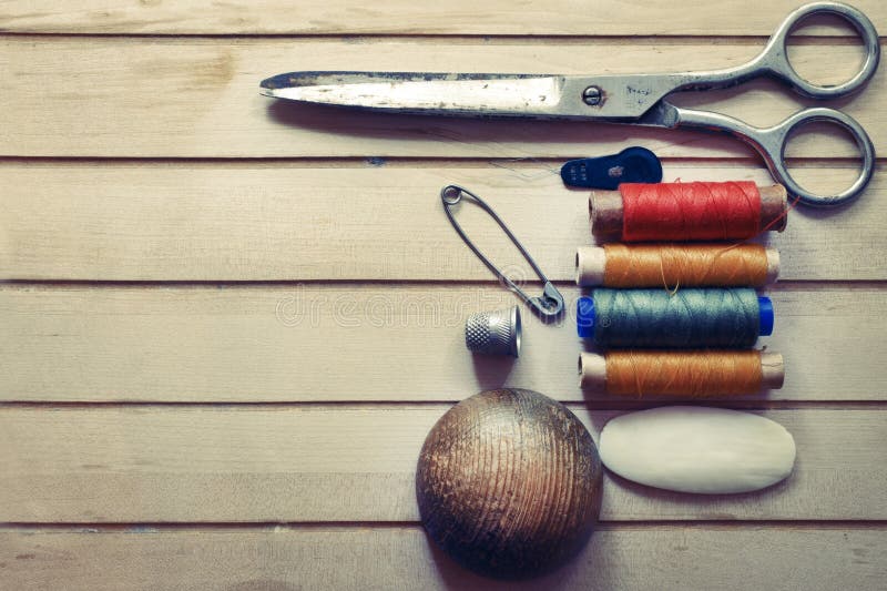 Old spool of thread with needle closeup. Tailor's work table. textile or fine cloth making.