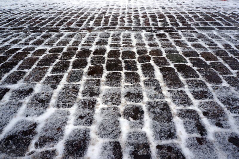 Old stone pavement covered with snow in winter