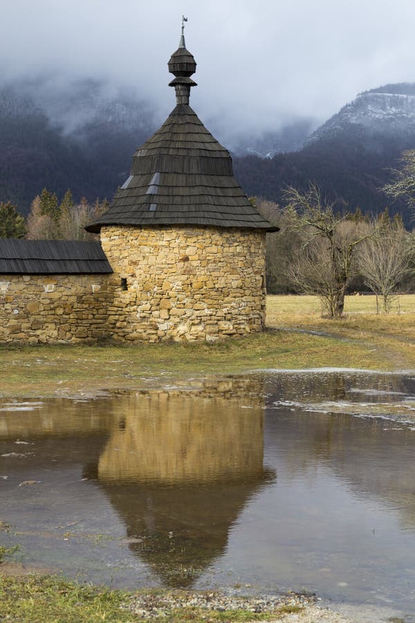 Old stone round tower with wooden roof on background of misty