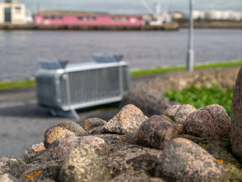 Old stone wall in town with safety features in focus, stack of metal crowd control barriers out of focus in the background. royalty free stock photography