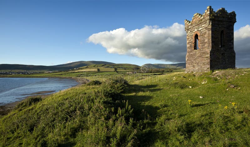 An old stone Watch tower over looking Dingle Bay Co. Kerry Ireland as a fishing boat heads out to sea.