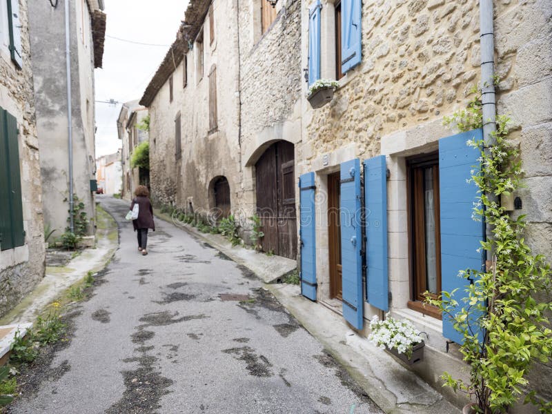 Old street with lonely figure and house with shutters and plants in manosque stock images Old street with lonely figure and house with shutters and plants in manosque stock images