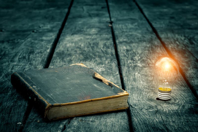 Old tattered book on a wooden table. Reading by candlelight. Vintage composition. Ancient library. stock image