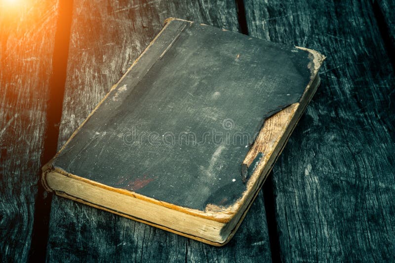 Old tattered book on a wooden table. Reading by candlelight. Vintage composition. Ancient library. stock image