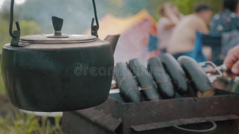 Old teapot boils on campfires. Fire, kettle, camping. Set fire to boil hot water in the kettle.