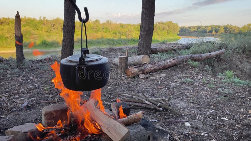 Old teapot boils on campfires. Fire, kettle, camping. Set fire to boil hot water in the kettle.