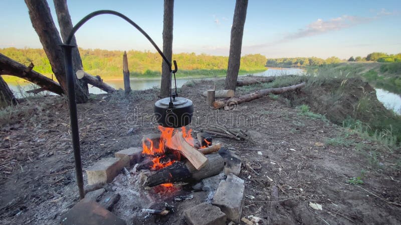 Old teapot boils on campfires. Fire, kettle, camping. Set fire to boil hot water in the kettle.