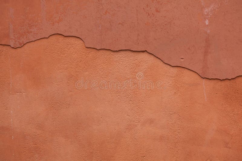 Old terracotta painted stucco wall with cracked plaster. Background texture