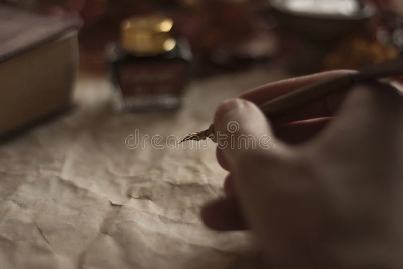 Old paper with a writing hand with feather pen and ink and Bible on wooden table