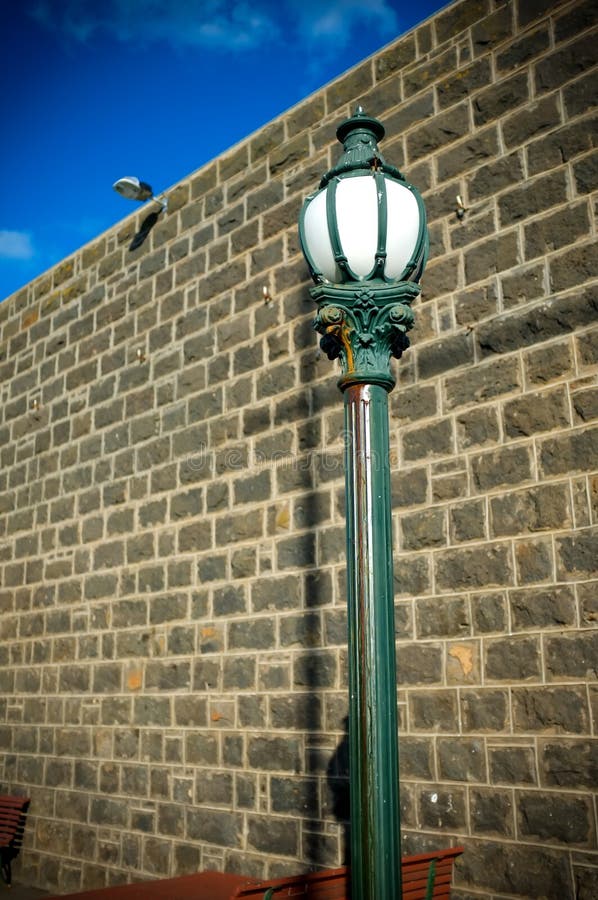 Old town street lamp post with wall and blue sky