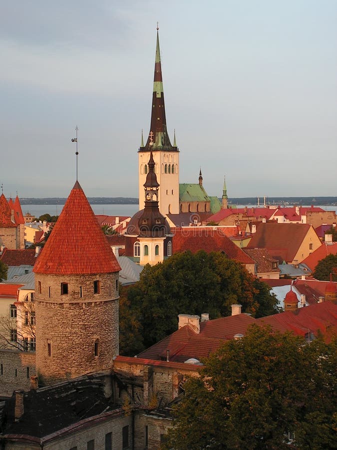 Scenic view of the old town of Tallinn  Estonia. Old stone towers  historic churches and city buildings in the warm sunset light with red stone rooftops. The Gulf of Finland in the background. Scenic view of the old town of Tallinn  Estonia. Old stone towers  historic churches and city buildings in the warm sunset light with red stone rooftops. The Gulf of Finland in the background.