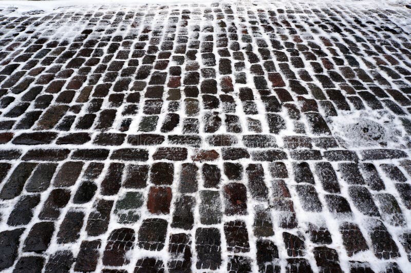 Old stone pavement covered with snow in winter