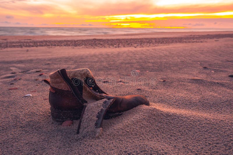 Old used boot lie half buried in desert sand dune in the evening light, landscape