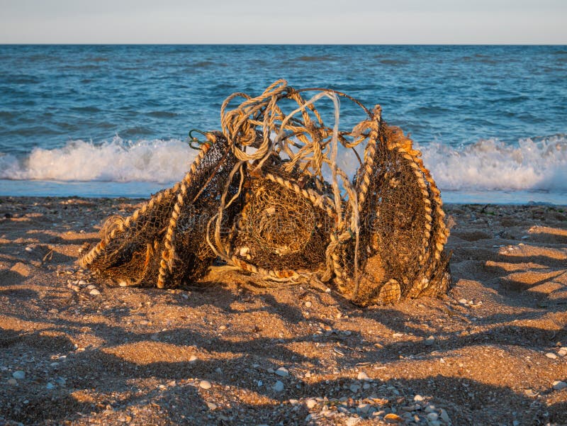 Old used dirty fishing nets with rusty wire, garbage dumped on sea beach sand. Environmental pollution problem concept