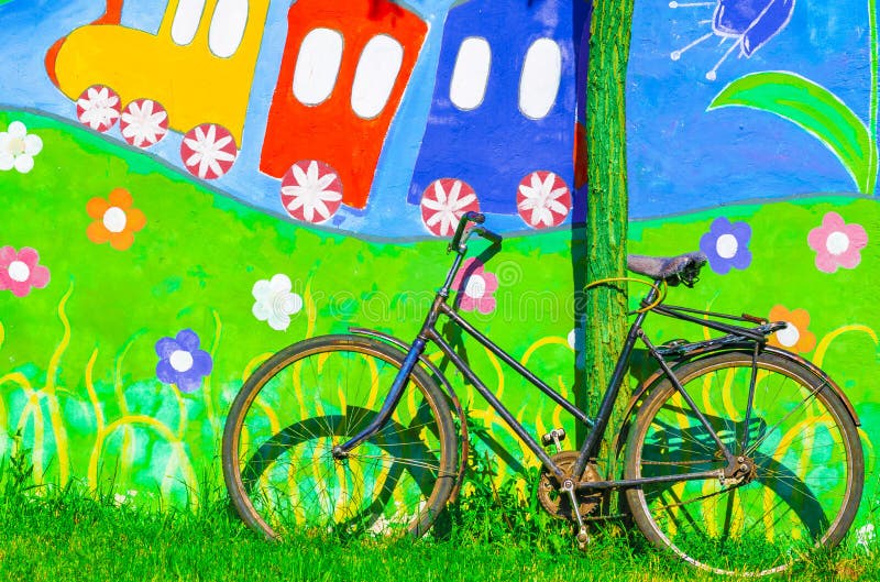 UKRAINE, POKROV - JULY 4, 2019: City park name Mozolevsky. Old vintage bicycle at the brightly painted colorful wall made by child royalty free stock photos UKRAINE, POKROV - JULY 4, 2019: City park name Mozolevsky. Old vintage bicycle at the brightly painted colorful wall made by child royalty free stock photos