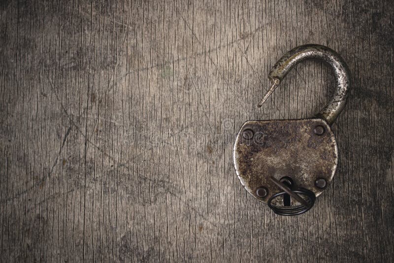 Old vintage lock with key. Ancient rusty barn lock with key on wooden textured background. royalty free stock images