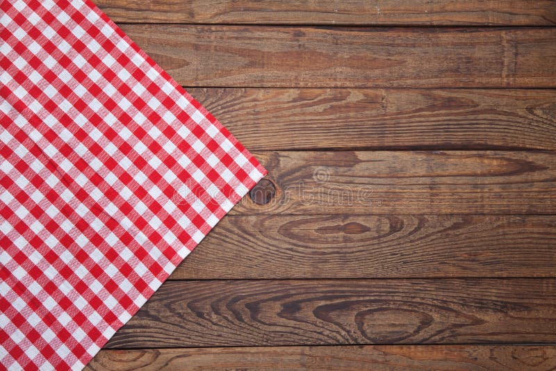 Old vintage wooden table with a red checkered tablecloth. Top view mockup.