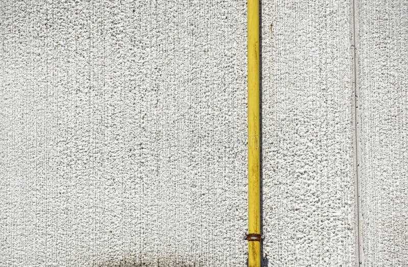 Old water metal pipes fixed with brackets in front of a plaster wall with metal box for water meter. royalty free stock image