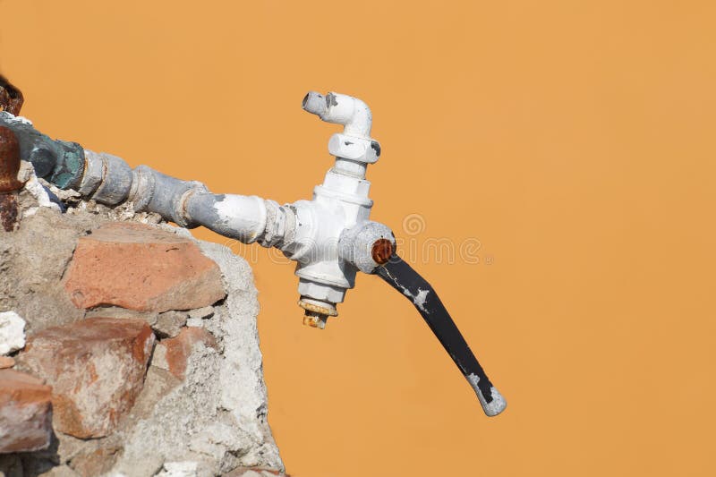 Old water tap with yellow wall background royalty free stock image