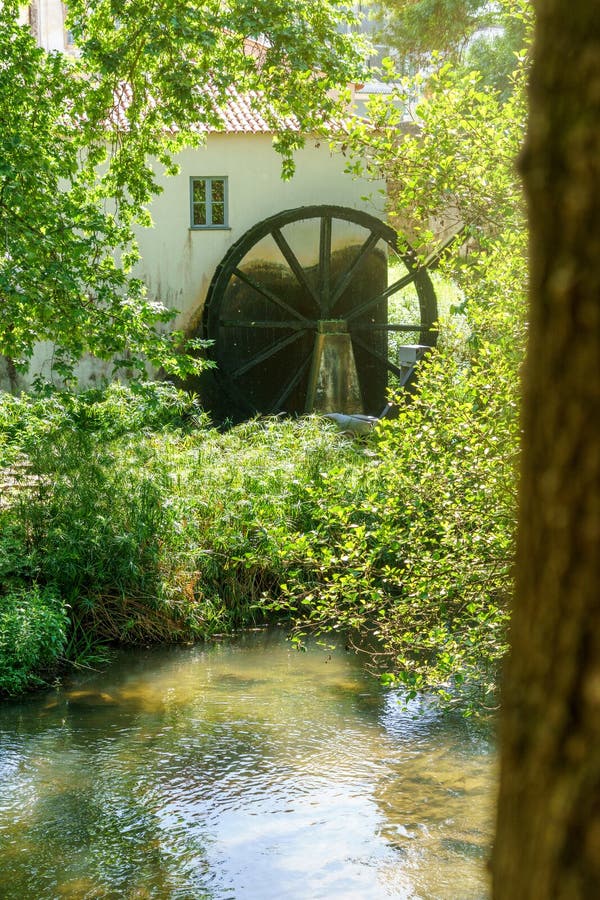 Old waterwheel mill house alongside a river. Working water mill alongside a millhouse for grinding grain and making paper