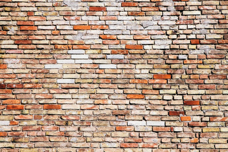 Old and weathered grungy yellow and red brick wall with visible crack as rustic rough texture background