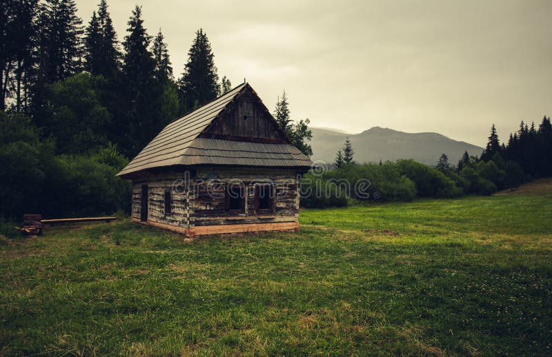 Old and weathered hut - chamkova stodol under the Kralova Hola mountain in rainy day. Old cabin in the green forest meadow with