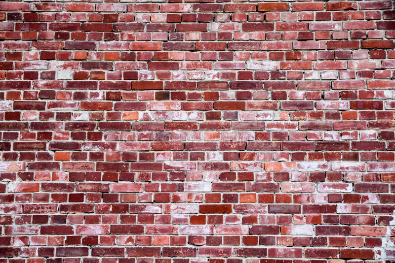 Old and weathered simple grungy red brick wall marked by the long exposure to the elements as texture background