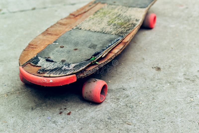 Old weathered skateboard on concrete surface stock images