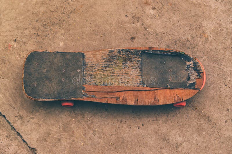 Old weathered skateboard on concrete surface stock photo