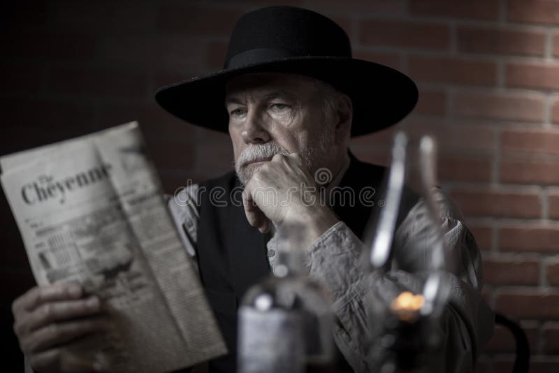 1885 old west cowboy sitting reading the newspaper