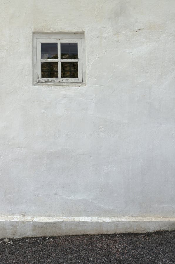 The old white plastered wall with a small window and a gravel pa stock image The old white plastered wall with a small window and a gravel pa stock image