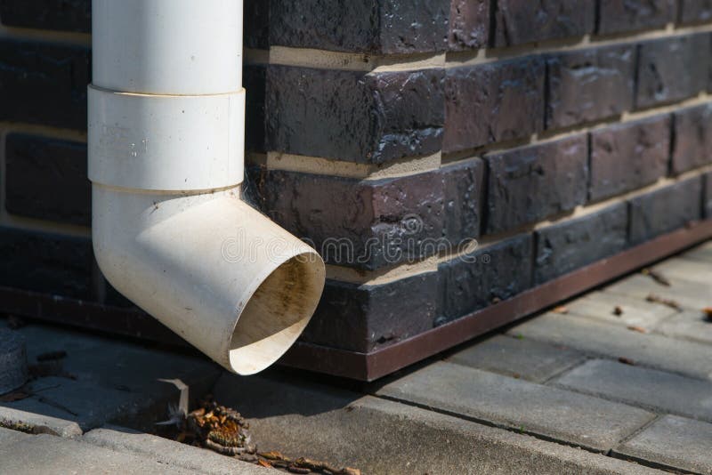 Old White Plastic Drain Pipe on the Brown Brick Wall Stock Image