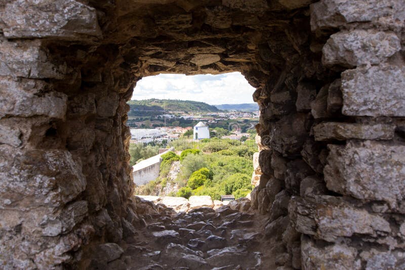 Old windmill through small window in fortress wall, Obidos