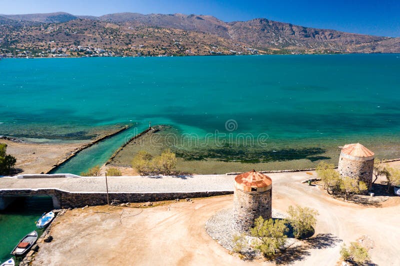 Old windmills and canal on a narrow causeway and site of an ancient Minoan city Elounda, Crete, Greece