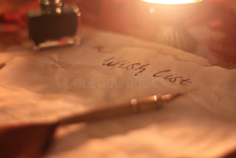 Old wishlist with feather pen and ink and candle on wooden table