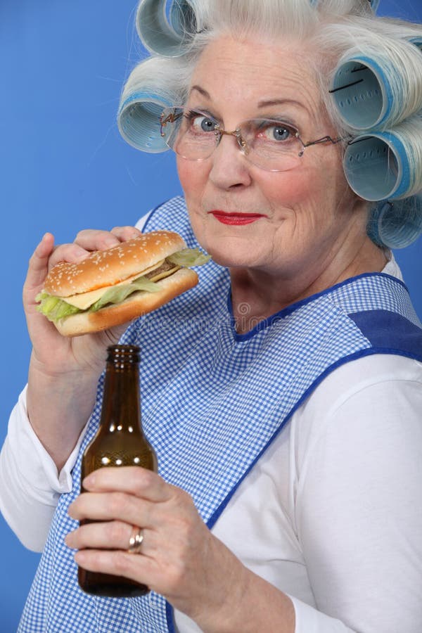 Old woman with a burger and beer. 