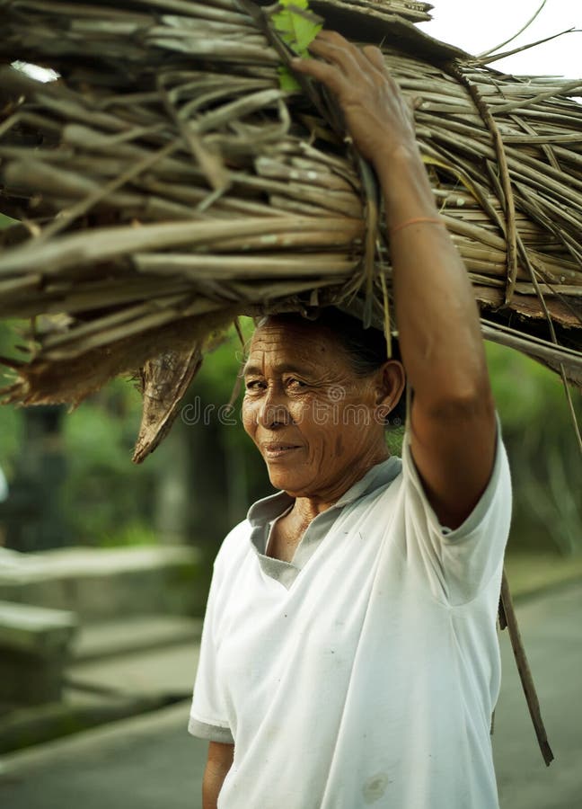 Old woman caring brushwood sheaf