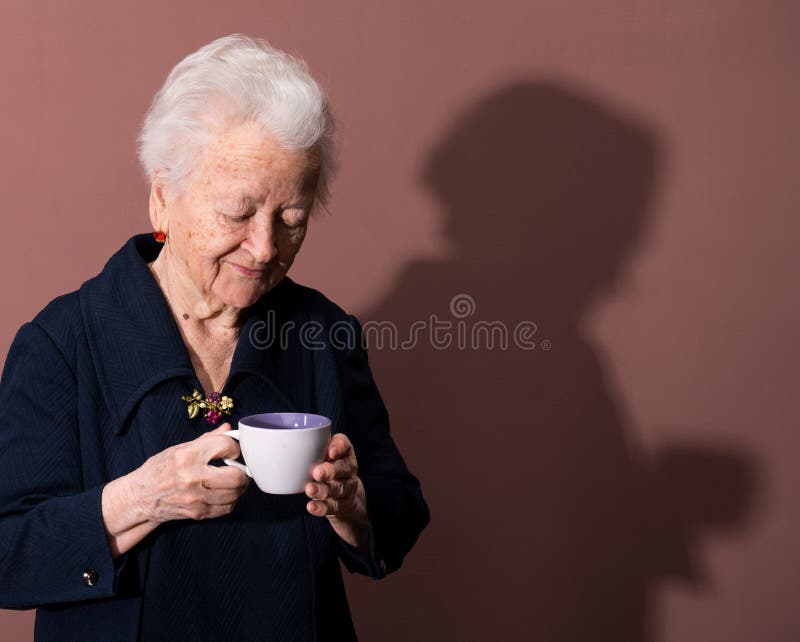 Old woman enjoying coffee or tea cup