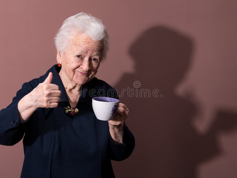 Old woman enjoying coffee or tea cup