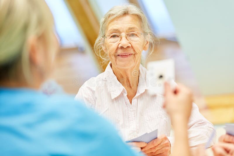 Old woman in card game with caregiver