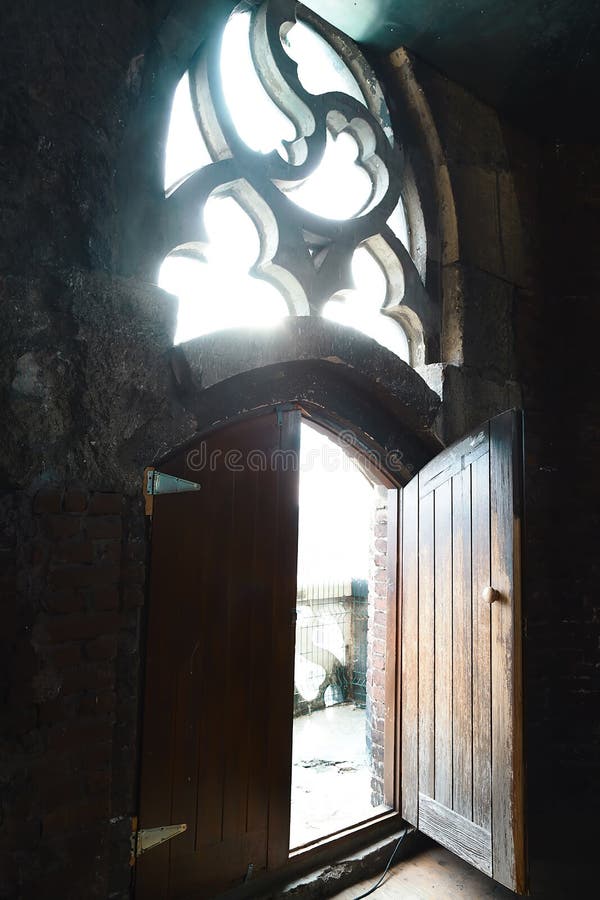 Old wood door with a small handle on red brick wall background, vintage window, rays of light, open door with two parts