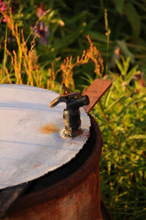 An old water barrel in a field on a beautiful summer evening in Norway royalty free stock photo An old water barrel in a field on a beautiful summer evening in Norway royalty free stock photo